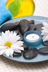 Fototapeta na wymiar Massage stones, candle and daisies