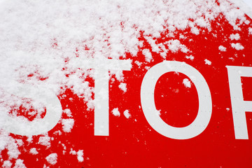 A bright red "stop" sign with a covering of snow