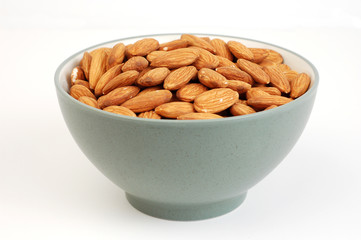 A bowl of shelled almond nuts on a white background.