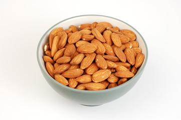 A bowl of shelled almond nuts on a white background.