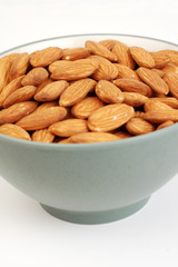 A bowl of shelled almond nuts on a white background.