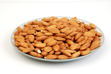 A plate of shelled almond nuts on a white background.