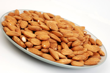 A plate of shelled almond nuts on a white background.