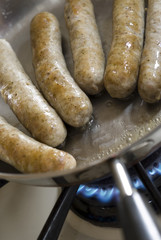 little pork sausage links frying in a pan