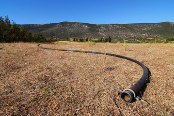 drought implied with dry pipe against arid farmland