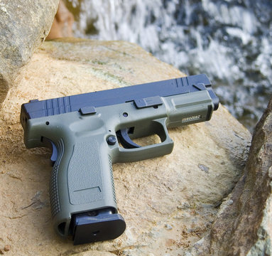 handgun with a waterfall in the background