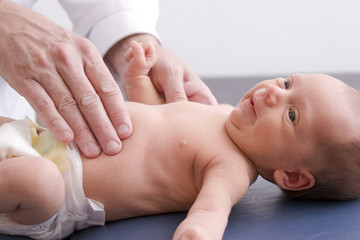 A doctor using his hands to palpate a newborn's abdomen