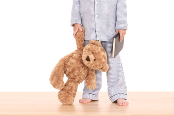 boy in pijama with his teddy bear and book isolated on white