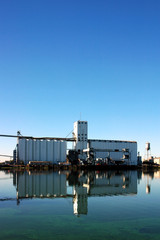 Naklejka premium Waterfront Grain Silo Reflected near Seaport Loading Docks