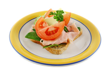 Ham lettuce tomato and cheese open sandwich on wholemeal bread.