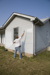 Fototapeta na wymiar Contractor spray painting exterior of house