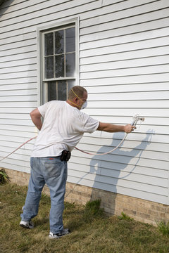 Contractor Spray Painting Exterior Of House