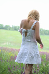 Fototapeta na wymiar Girl in white dress going away on meadow