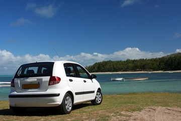 Fototapeta na wymiar Biały mały samochód na zielonej trawie przy plaży