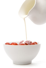 Cream being poured over a bowl of strawberries