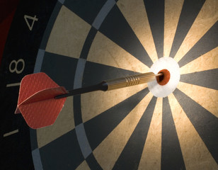 Bullseye on a dark dartboard with a big red dart