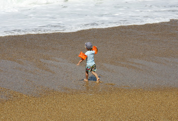 petit garçon qui court sur la plage avec des brassard © bacalao
