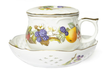 teacup on saucer decorated with fruit and berries