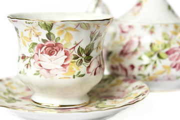 teacup on saucer against sugar bowl decorated with roses
