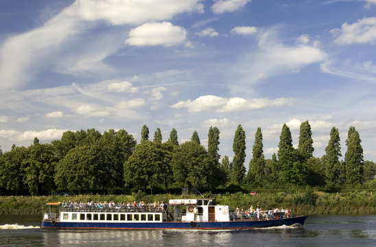 Tourist boat on River Thames with trees at the background