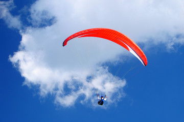 Red paraglider on blue sky