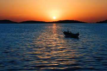 Magnificent sunset and anchored boat at sea