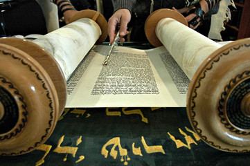 Torah  in a synagogue with a hand holding a silver pointer