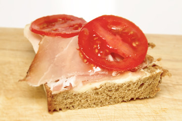 Ein Speckbrot mit Tomaten auf einem Brett