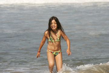 Fototapeta na wymiar petite fille en maillot de bain qui court sur la plage