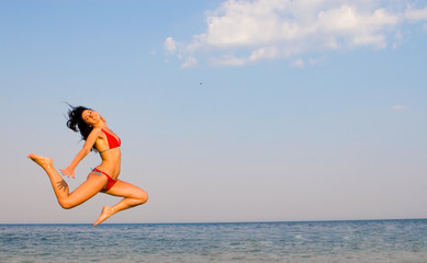 happy young woman is jumping in beach