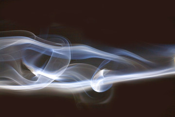 white smoke gently flowing across a black background.
