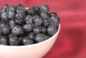 Blueberries in a bowl with a wine colored background