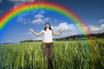 young girl with arms wide open contemplating the rainbow