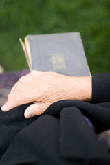 Obraz na płótnie Canvas Senior's hands on old book