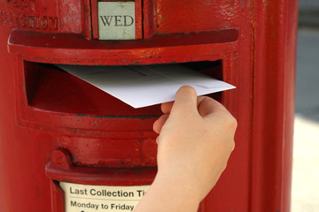 posting a  letter to red british postbox on street