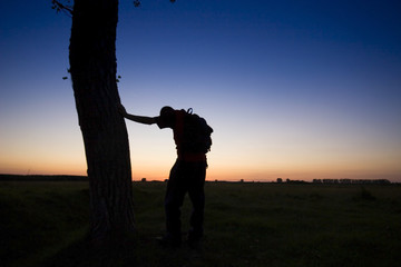 A man's silhouette in the sunset with a tree