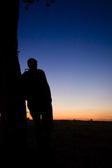 A man's silhouette in the sunset with a tree