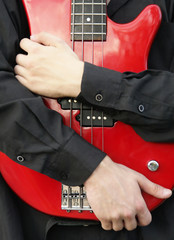 man embracing a red bass guitar