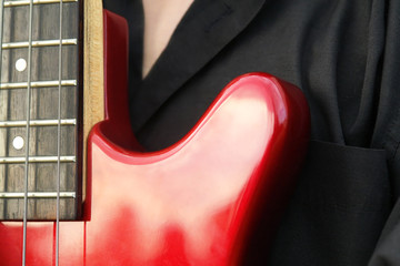 man in black shirt with a red bass guitar