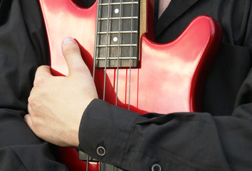man's hand embracing a red bass quitar
