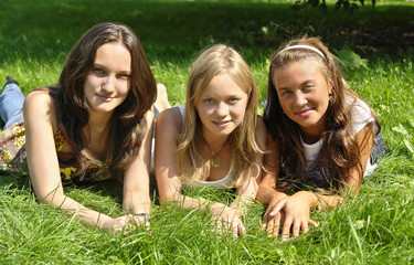 three beautiful young girls lying on the grass