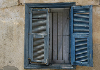 Weathered blue shutters on a window at an old house