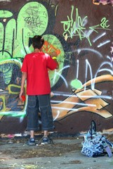 Adolescent en train de peindre un graffiti sur un mur
