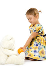 Little girl with orange and bear toy.