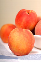 A white bowl containing fresh peaches