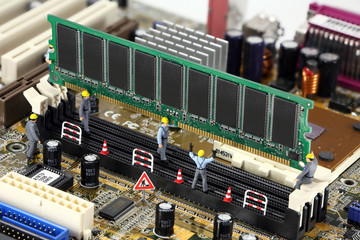 Miniature construction workers installing RAM on a motherboard