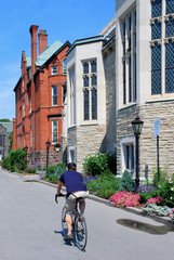 Fototapeta premium Student riding bicycle past bookstore at a gothic style college 