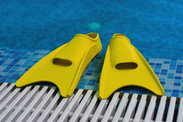 Yellow flippers on coast of swimming pool