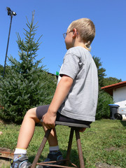 Kind sitzt auf einem Melkschemel und beobachtet etwas