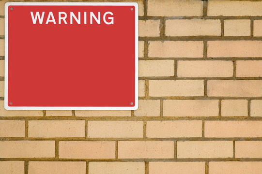 Warning sign on brick wall.